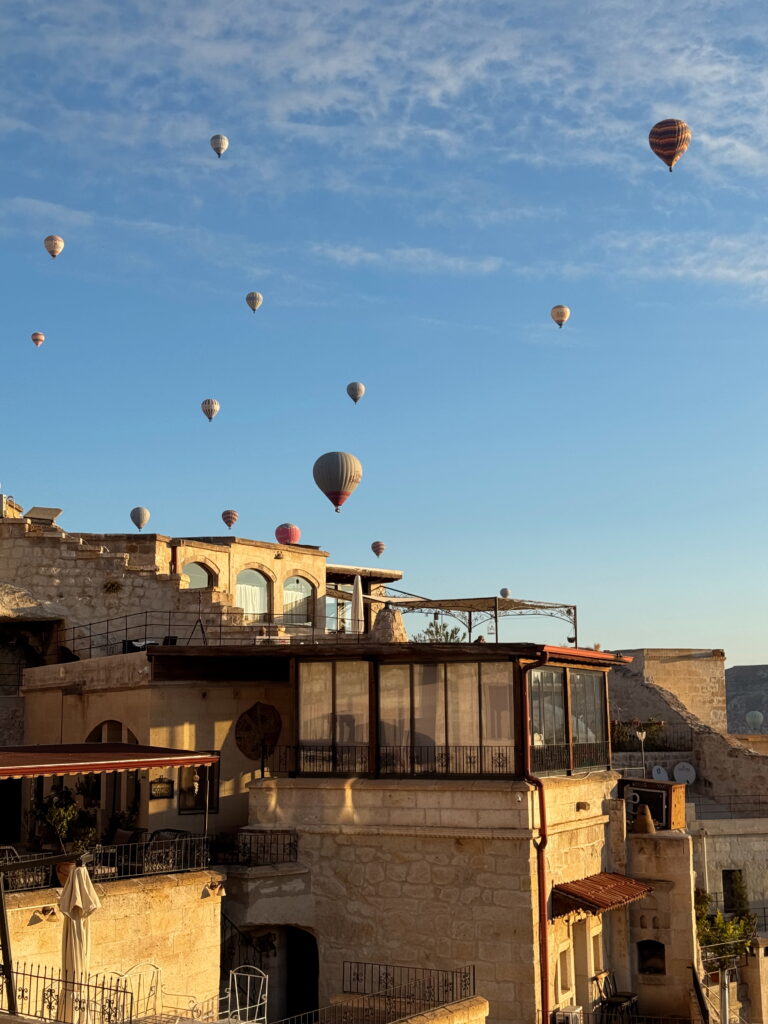 Sunrise balloons over the rooftop in Cappadocia